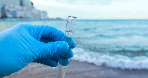 a scientist holding a vial of water studying ocean chemistry