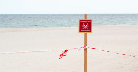 a sign on a dangerous beach in ukraine warning of landmines