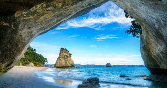 a view of tyhe ocean from inside of a cave in new zealand