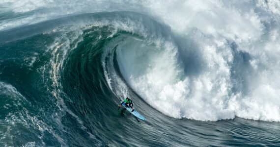 a surfer riding a massive wave in nazare portugal
