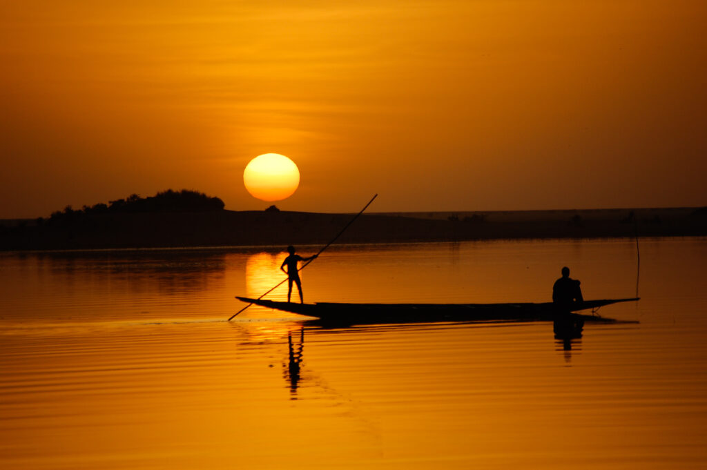 lone fisherman in a boat on the niger river at sunset