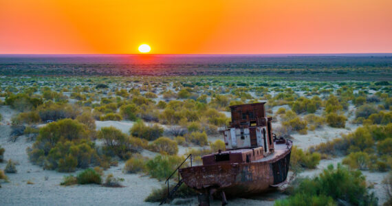 a boat in the desert at sunset