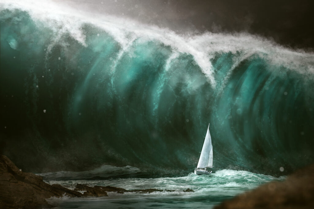 a massive wave behind a small sailboat