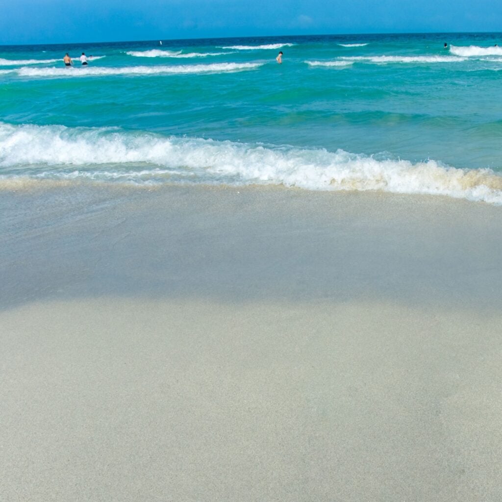 Waves gently roll onto the soft white sand of Grayton Beach, where clear emerald water and a peaceful shoreline offer a relaxing Florida coastal escape.