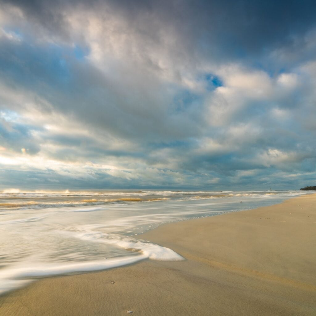 Sunset on Sullivan's Island, SC, with rocks and beach in foreground.