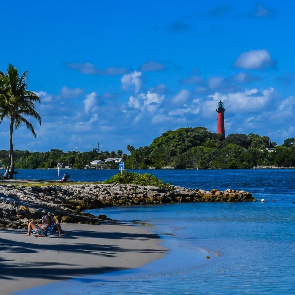 The Jupiter, Florida lighthouse as tourists enjoy the beach on the inlet from the Atlantic Ocean.