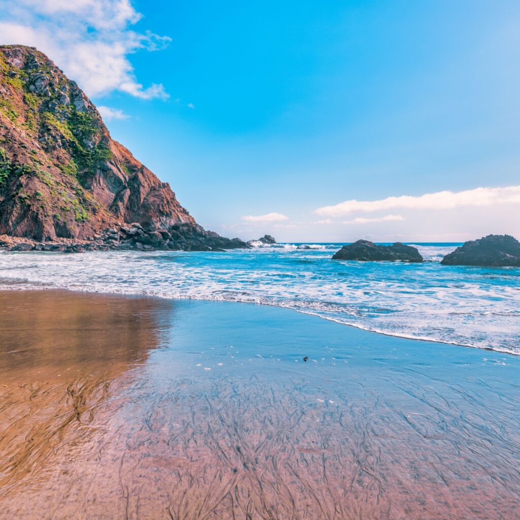 Breathtaking view of Pfeiffer Beach in Big Sur, California, featuring its iconic rock arch, golden sand, and turquoise waves. A stunning coastal landscape perfect, for travel and nature lovers.