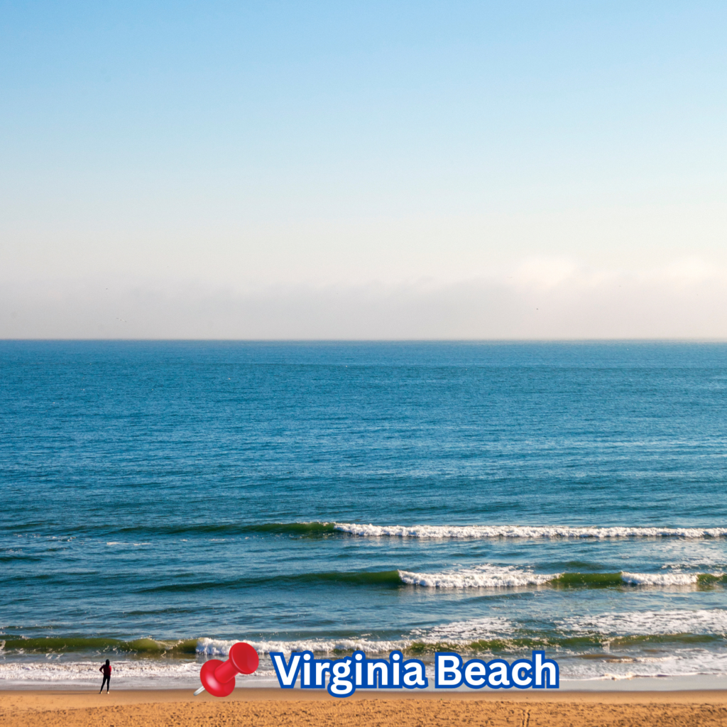 Peaceful morning at Virginia Beach with gentle waves rolling in, golden sand in the foreground, and a lone person walking along the shoreline under a clear sky.








