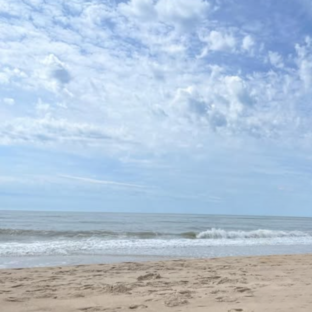 Soft waves meet the sandy shore at Hither Hills State Park in Montauk, under a lightly clouded sky with calm ocean views and a peaceful beach setting.